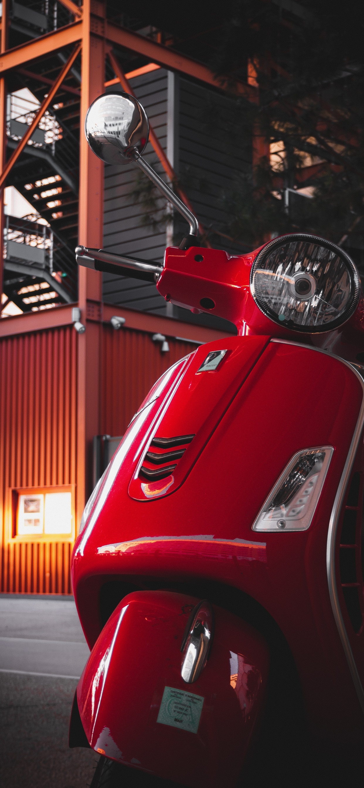 Red Motor Scooter Parked Near Building. Wallpaper in 1242x2688 Resolution