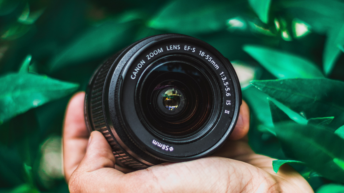 Person Holding Black Nikon Camera Lens. Wallpaper in 1366x768 Resolution