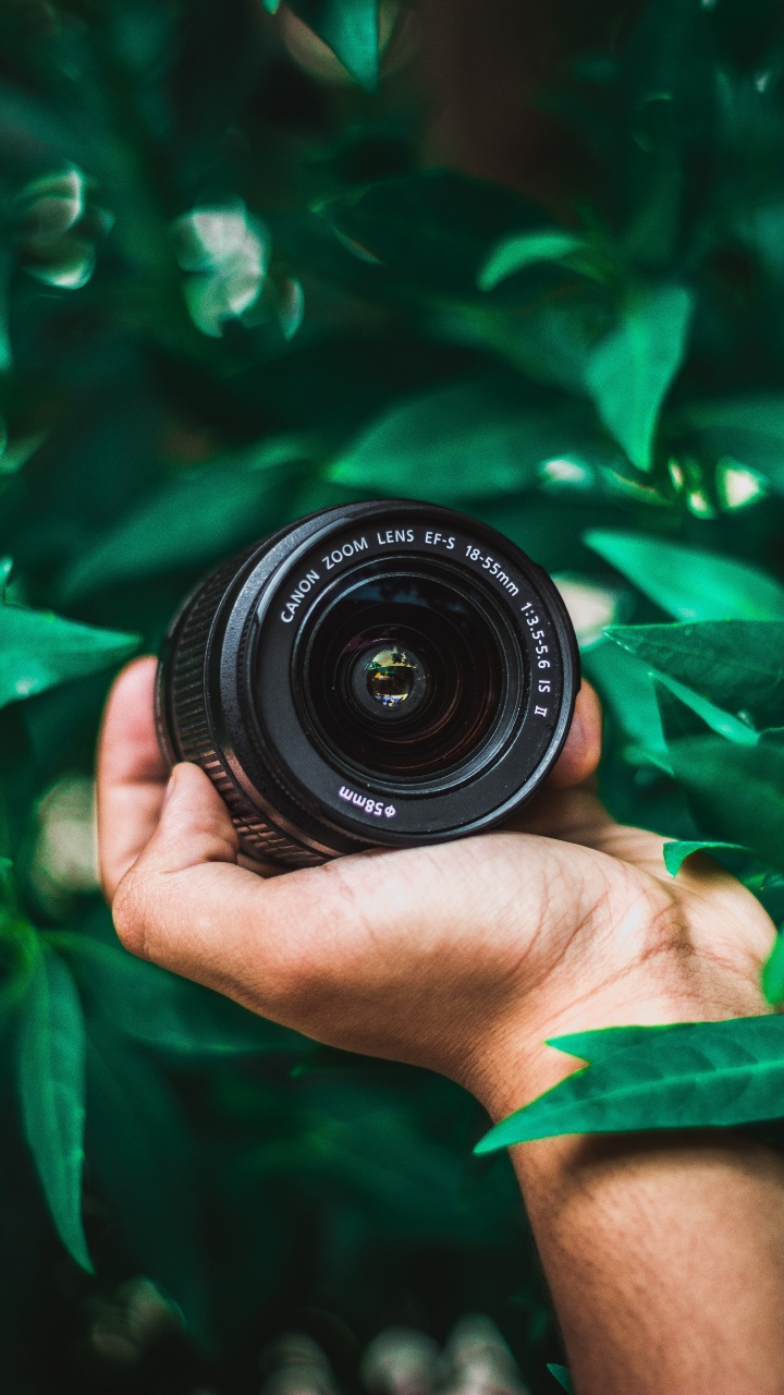 Person Holding Black Nikon Camera Lens. Wallpaper in 720x1280 Resolution