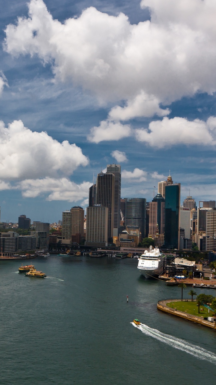 Bateau Blanc et Bleu Sur la Mer Près Des Bâtiments de la Ville Sous Des Nuages Blancs et un Ciel Bleu Pendant. Wallpaper in 720x1280 Resolution