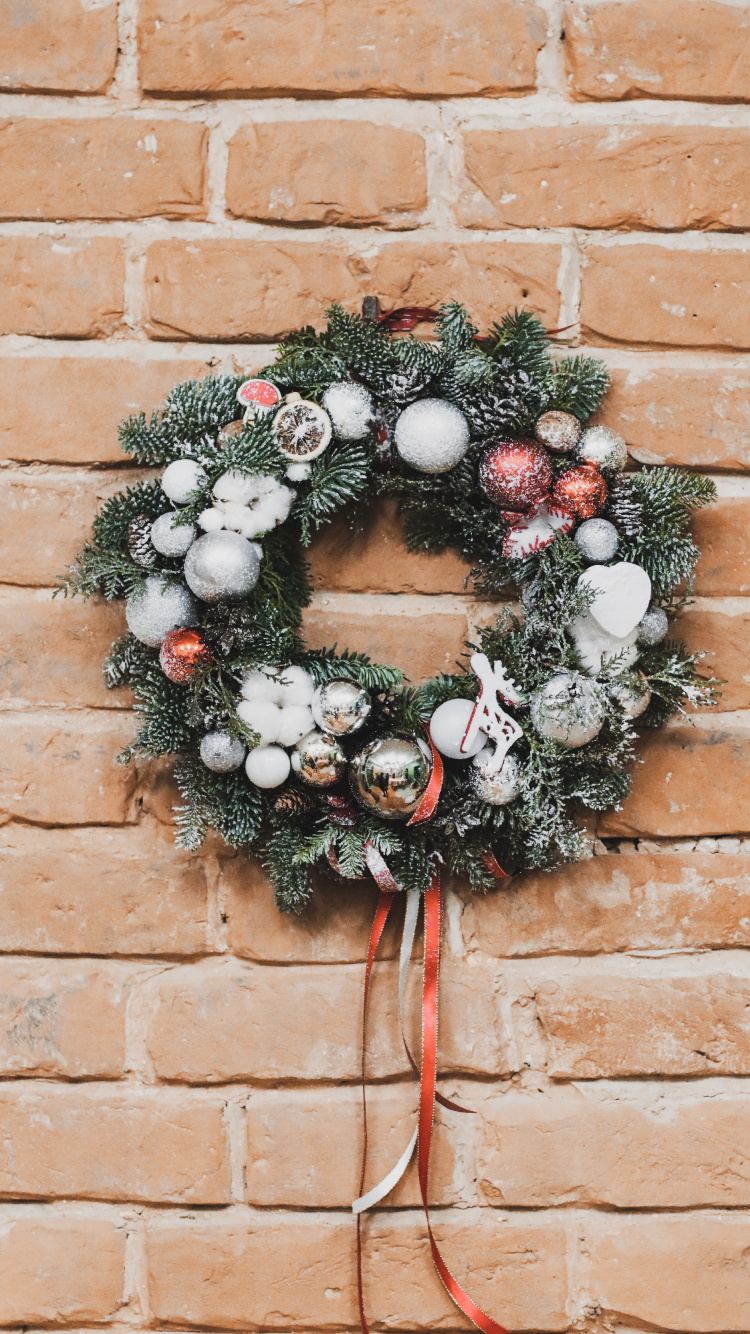 Grün-weißer Kranz Auf Brauner Backsteinmauer. Wallpaper in 750x1334 Resolution