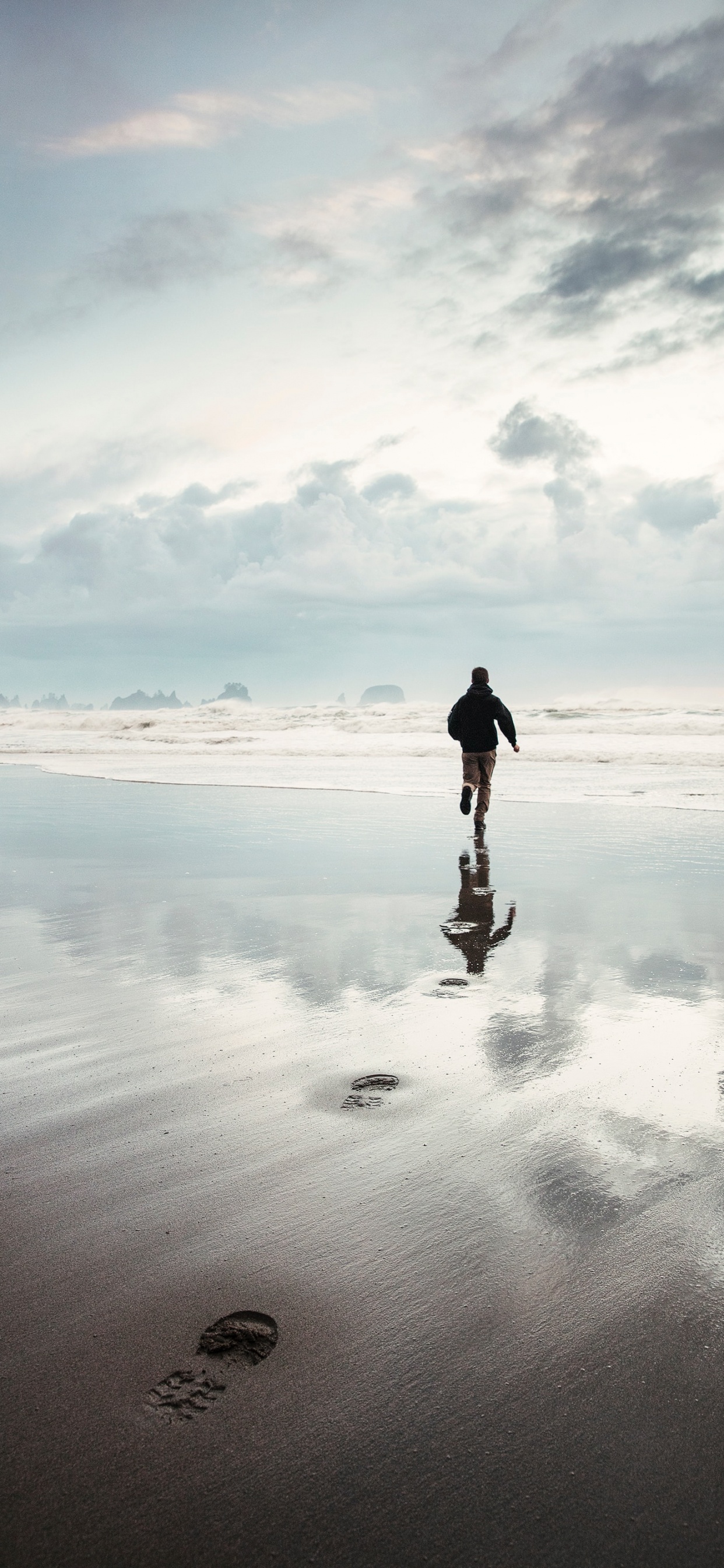 Homme en Veste Noire Marchant Sur la Plage Pendant la Journée. Wallpaper in 1242x2688 Resolution