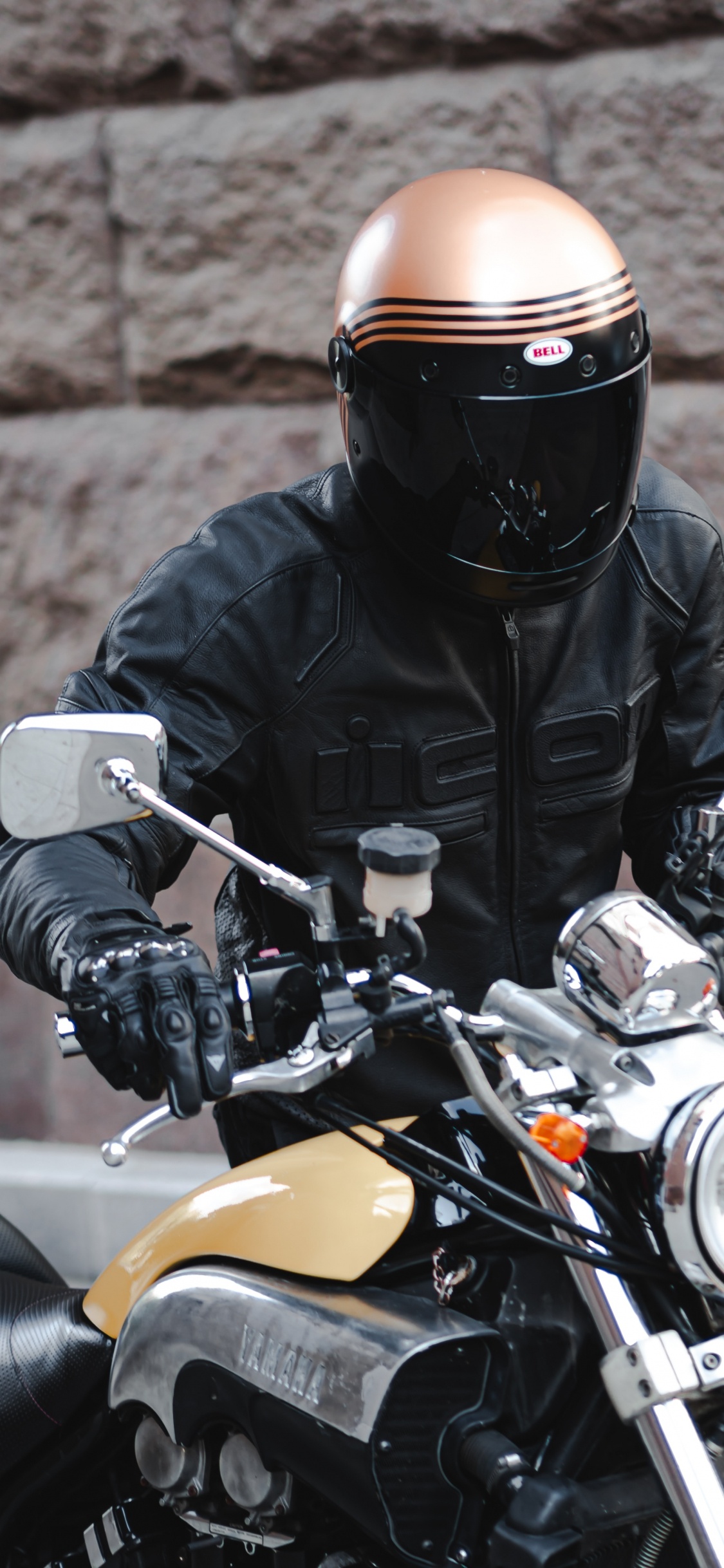 Mann in Schwarzer Lederjacke Mit Schwarzem Helm Auf Gelbem Motorrad. Wallpaper in 1125x2436 Resolution