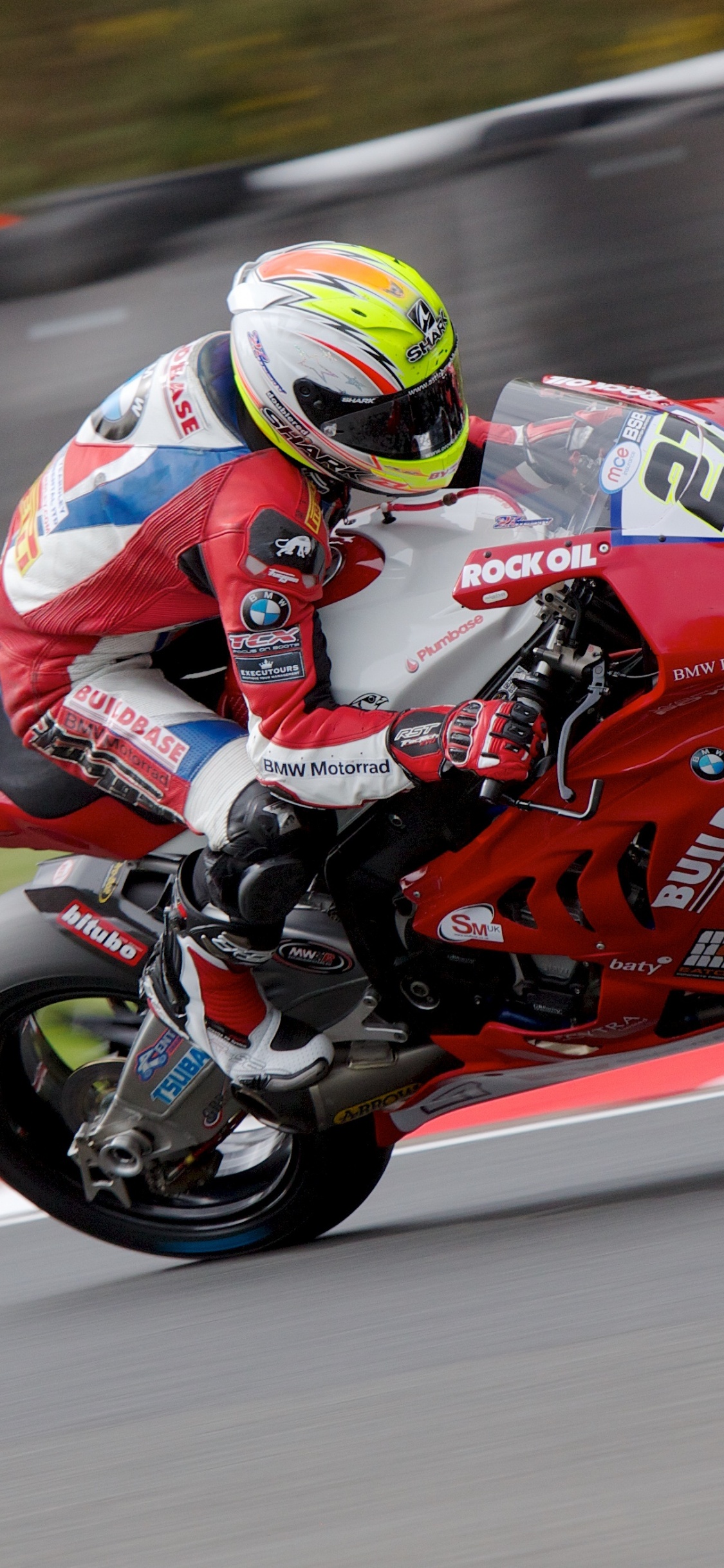 Man in Red and Black Motorcycle Suit Riding on Red Sports Bike. Wallpaper in 1125x2436 Resolution