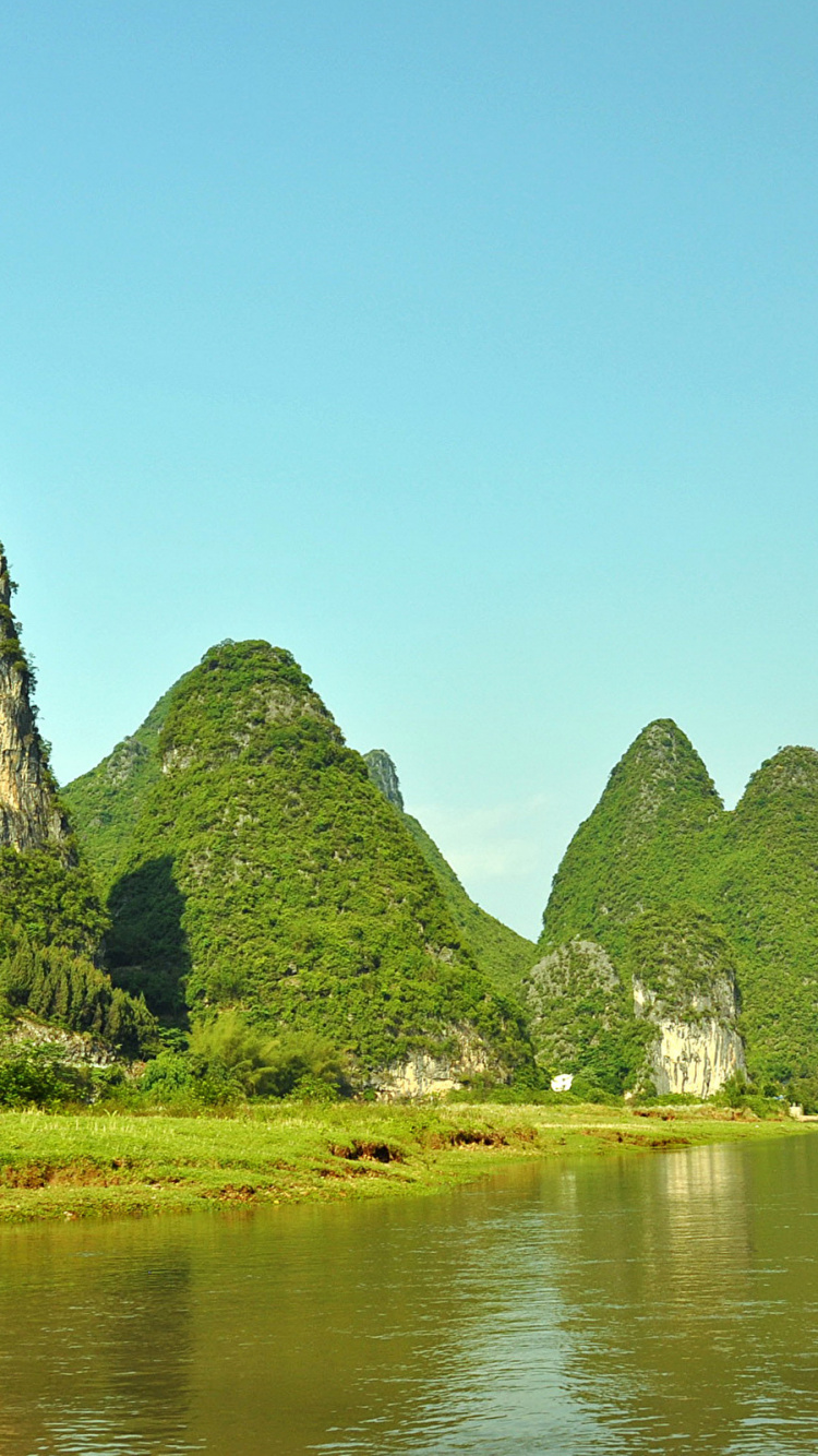 Green and Brown Mountain Beside Body of Water During Daytime. Wallpaper in 750x1334 Resolution