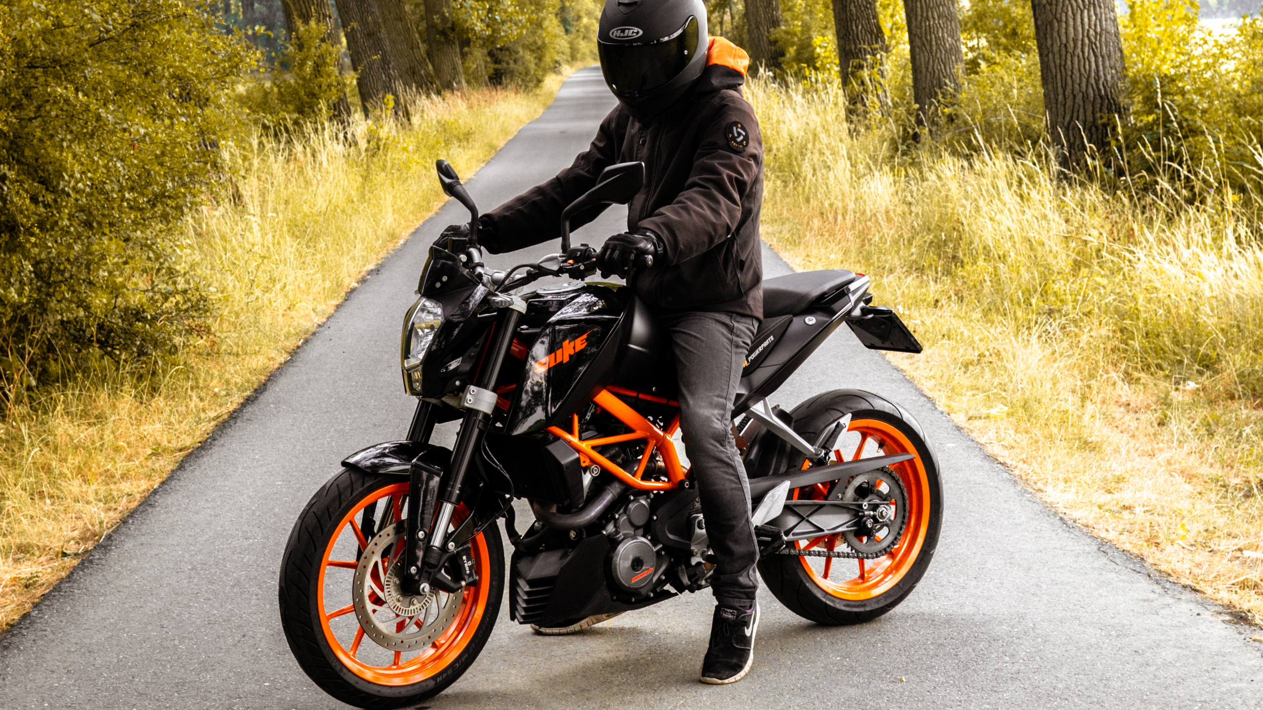 Mann in Schwarzer Jacke, Der Tagsüber Schwarzes Motorrad Auf Der Straße Fährt. Wallpaper in 2560x1440 Resolution