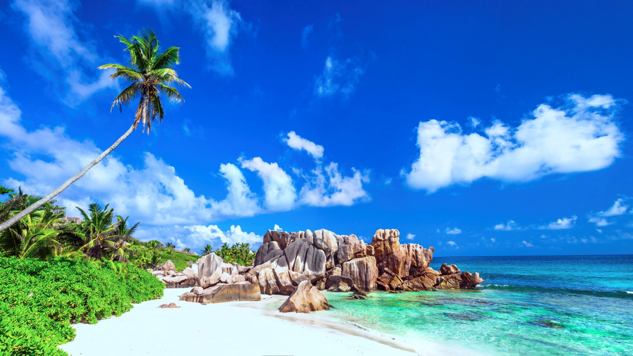 Brown Rocky Mountain Beside Body of Water Under Blue Sky and White Clouds During Daytime. Wallpaper in 1280x720 Resolution