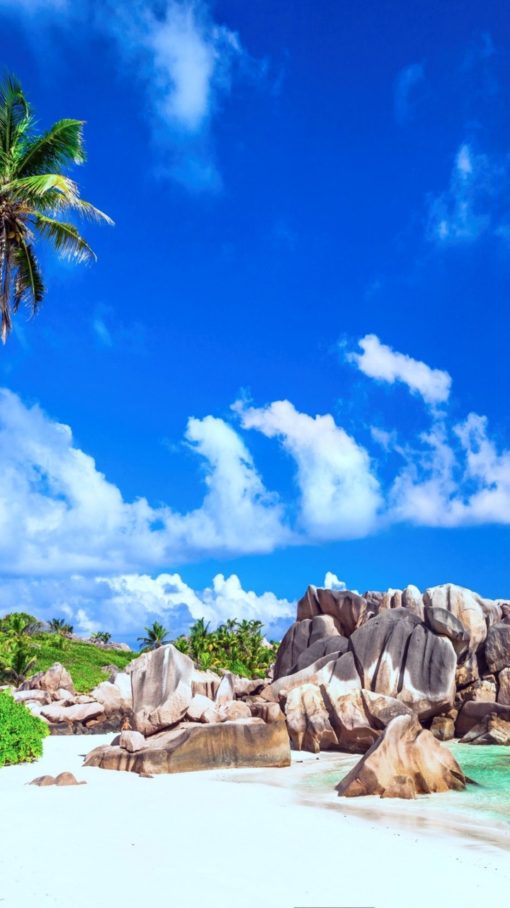 Montaña Rocosa Marrón Junto al Cuerpo de Agua Bajo un Cielo Azul y Nubes Blancas Durante el Día. Wallpaper in 720x1280 Resolution