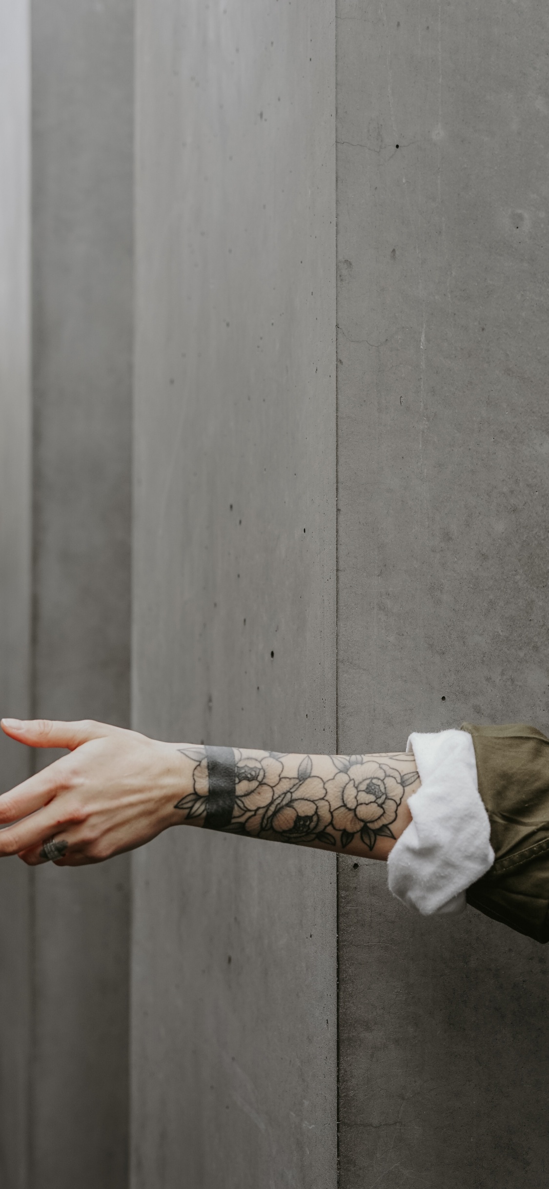 Person in Brauner Jacke Mit Schwarzem Tattoo an Der Linken Hand. Wallpaper in 1125x2436 Resolution