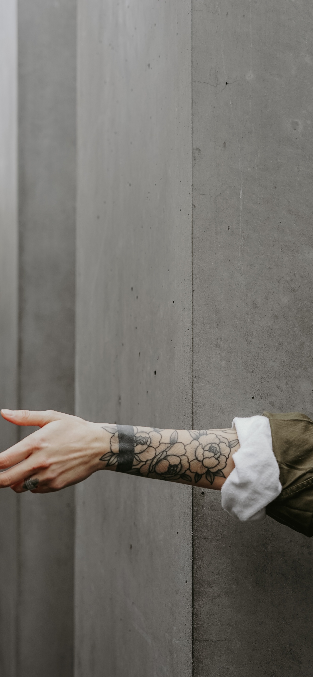 Person in Brauner Jacke Mit Schwarzem Tattoo an Der Linken Hand. Wallpaper in 1242x2688 Resolution