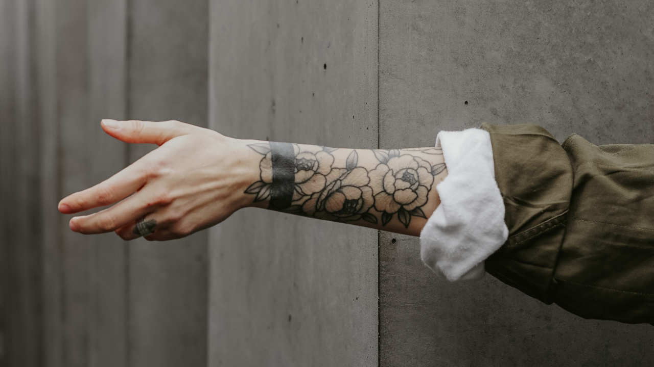 Person in Brauner Jacke Mit Schwarzem Tattoo an Der Linken Hand. Wallpaper in 1280x720 Resolution