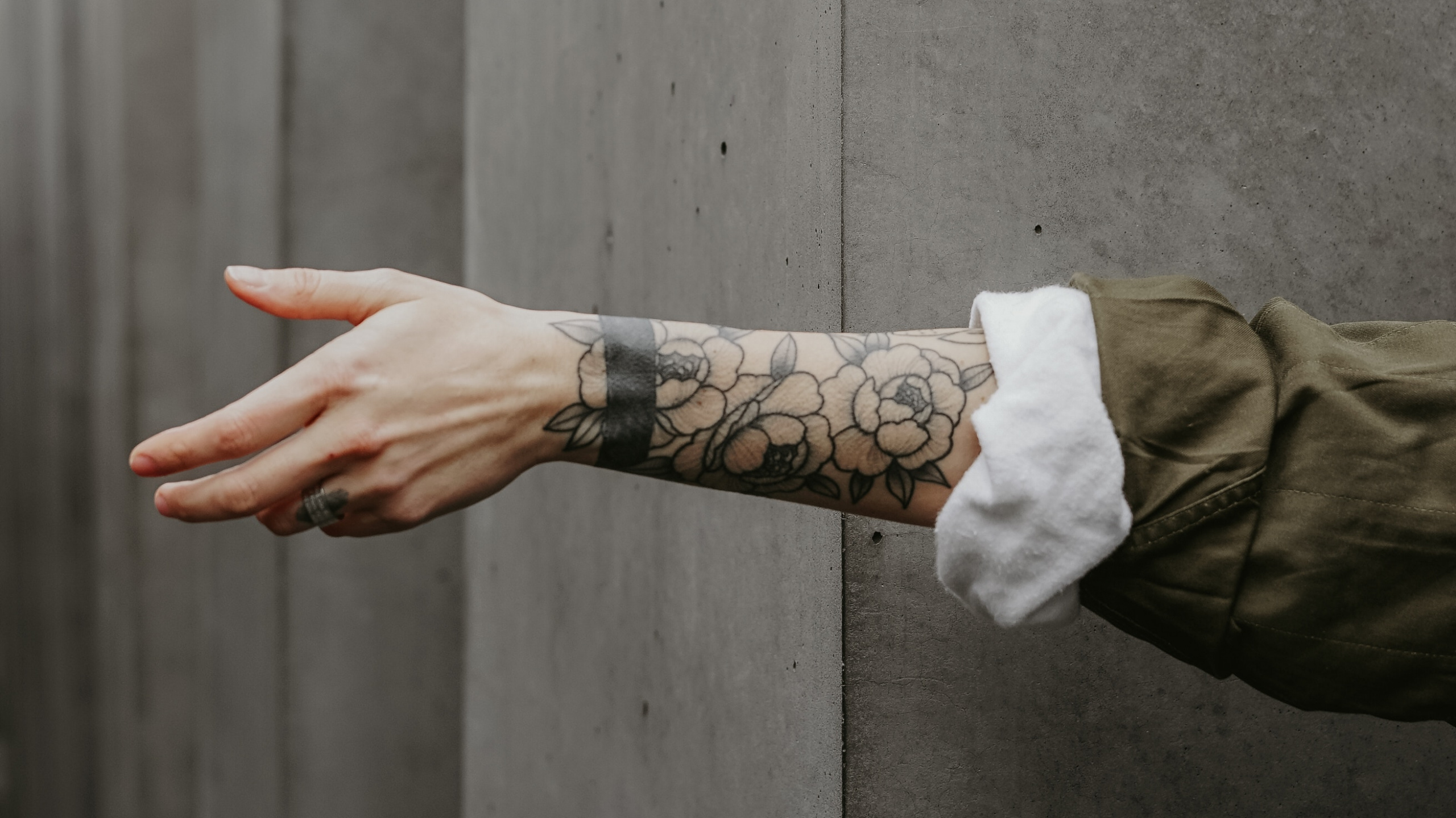 Person in Brauner Jacke Mit Schwarzem Tattoo an Der Linken Hand. Wallpaper in 2560x1440 Resolution