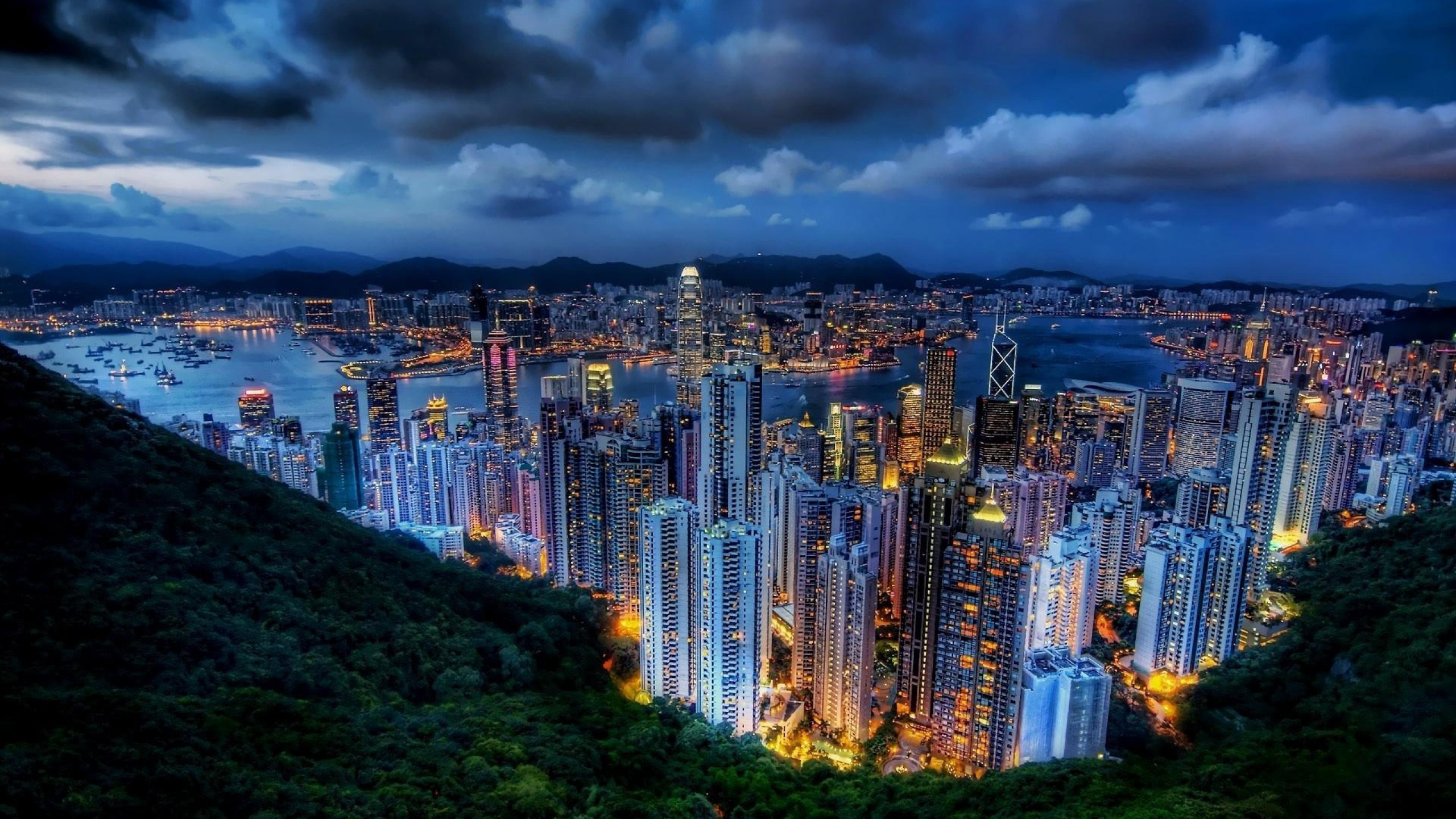 City Skyline Under Gray Cloudy Sky During Night Time. Wallpaper in 2560x1440 Resolution