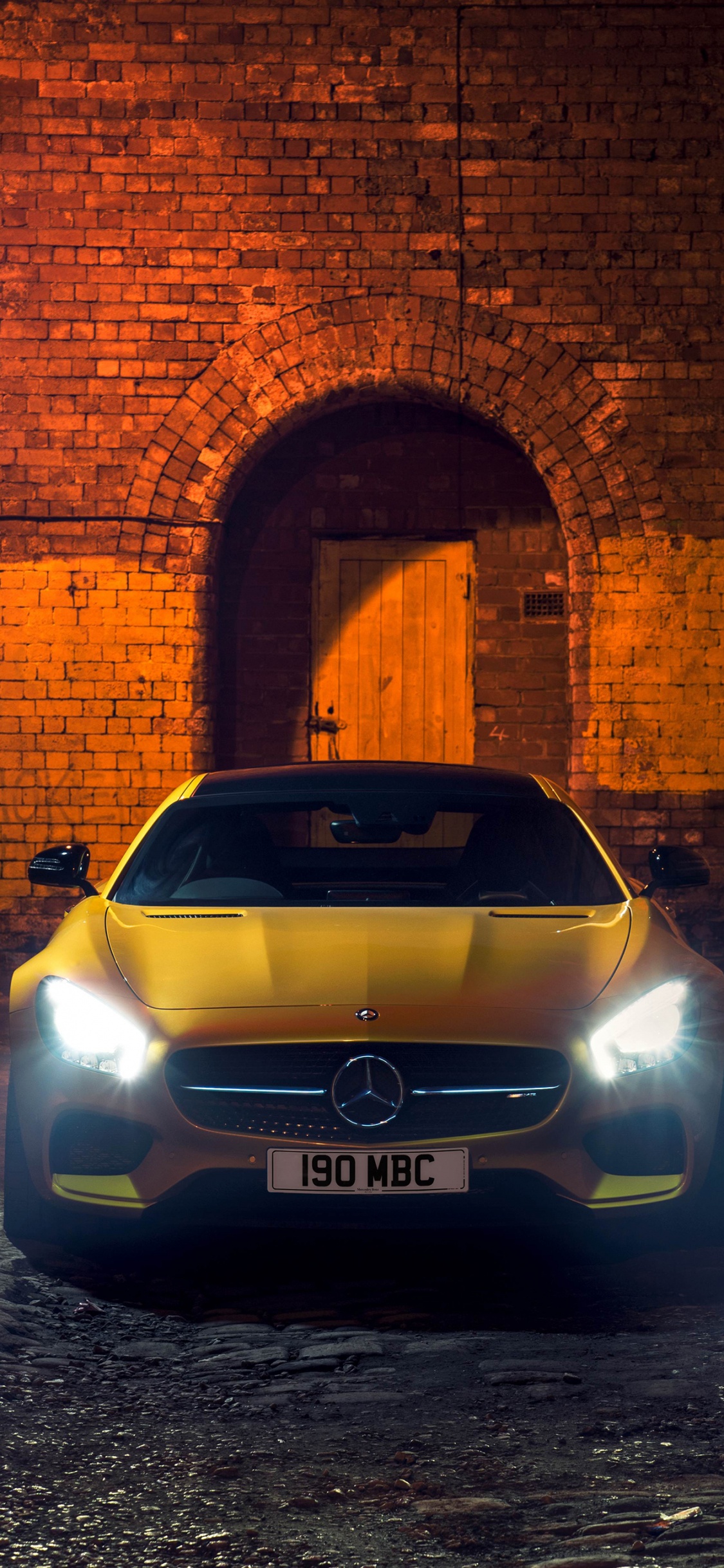 Silver Car Parked Beside Brown Brick Wall. Wallpaper in 1125x2436 Resolution