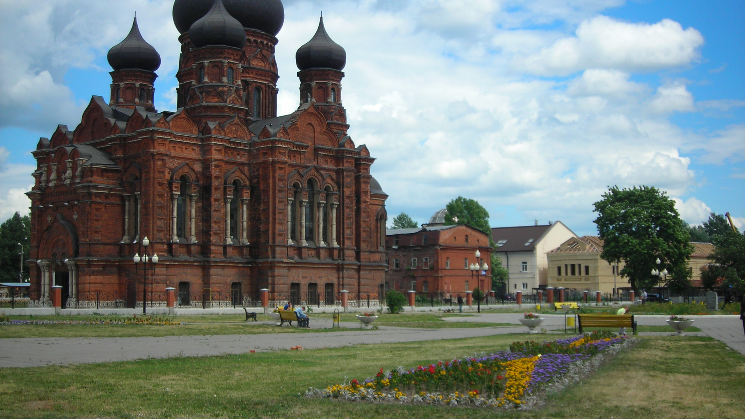 Braunes Betongebäude in Der Nähe Von Grünem Grasfeld Unter Weißen Wolken Tagsüber. Wallpaper in 2560x1440 Resolution