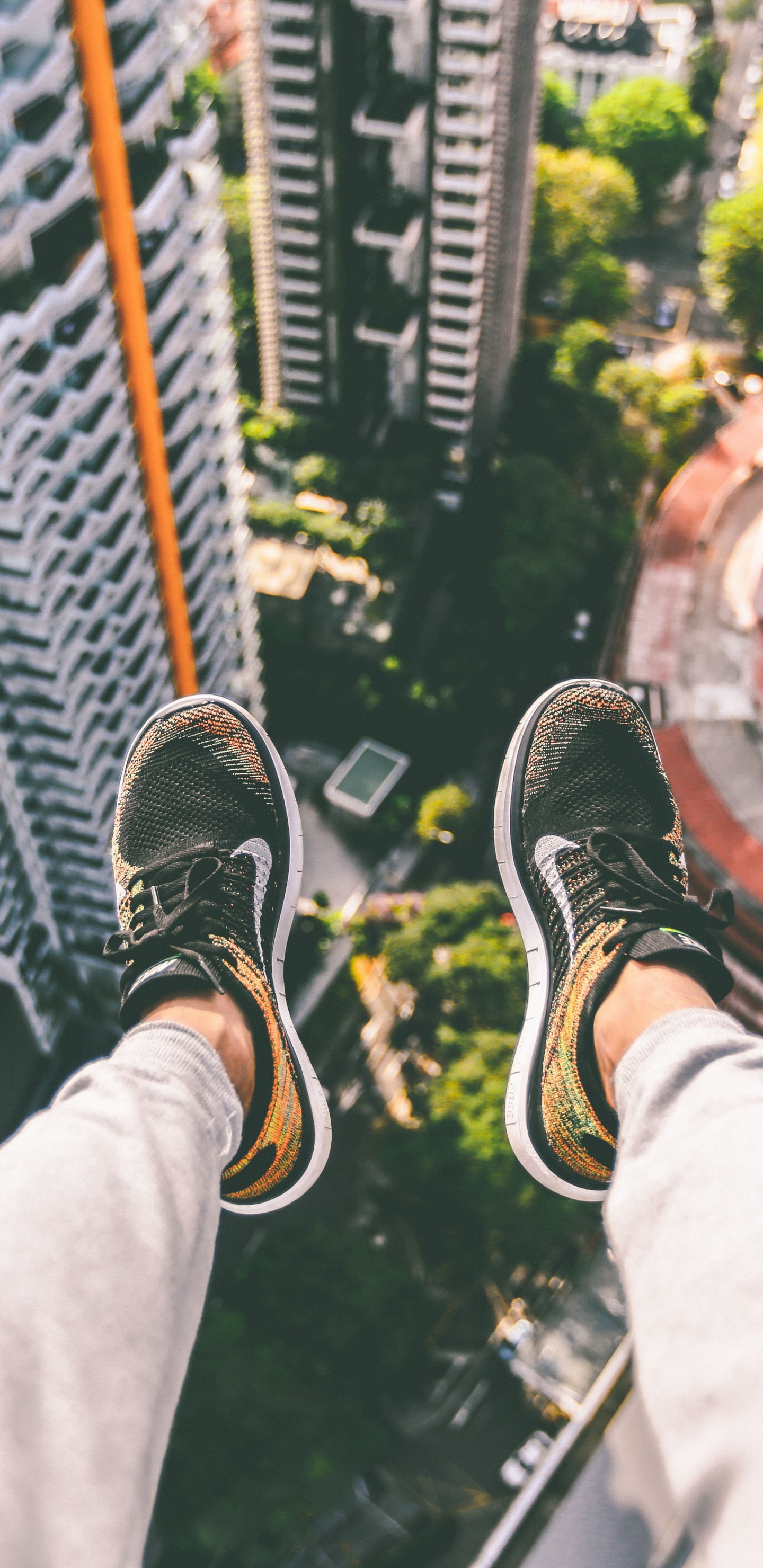Person in Black and White Sneakers Sitting on Top of Building. Wallpaper in 1440x2960 Resolution