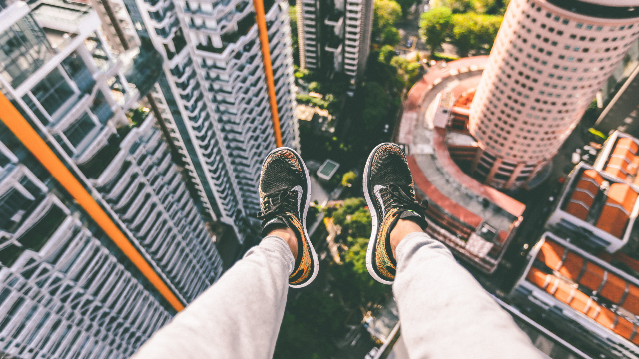 Person in Schwarz-weißen Turnschuhen, Die Auf Einem Gebäude Sitzt. Wallpaper in 1280x720 Resolution