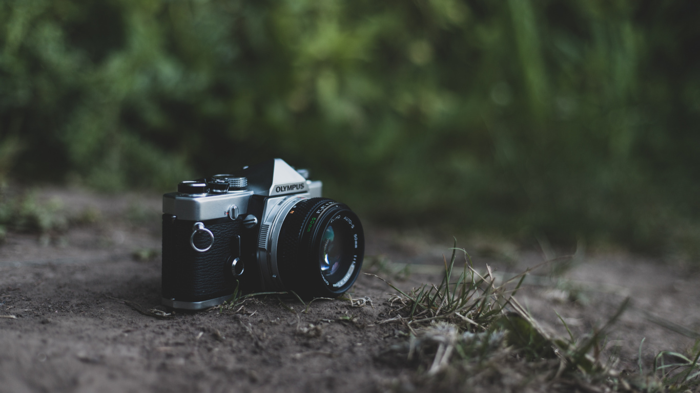 Schwarze Und Silberne DSLR-Kamera Auf Grünem Gras. Wallpaper in 1366x768 Resolution