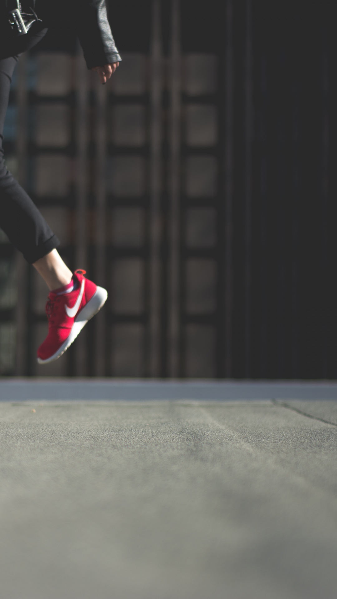 Person in Black Pants and Pink Nike Sneakers Jumping on Black Asphalt Road. Wallpaper in 1080x1920 Resolution