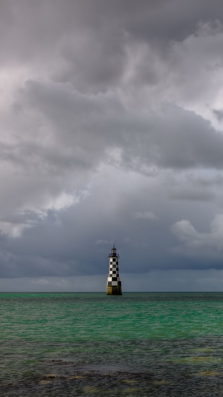 Weißer Und Schwarzer Leuchtturm Auf Dem Meer Unter Weißen Wolken Und Blauem Himmel Tagsüber. Wallpaper in 750x1334 Resolution