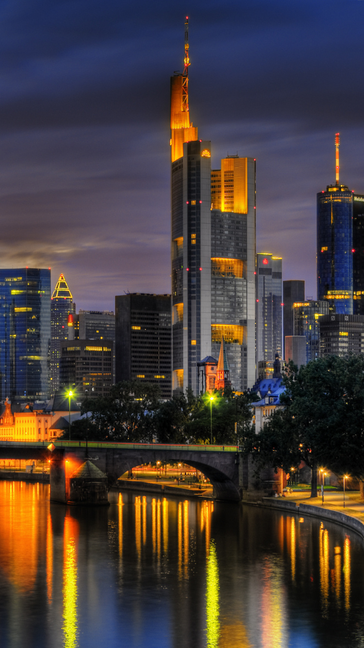 Skyline Der Stadt Über Gewässer Während Der Nacht. Wallpaper in 750x1334 Resolution