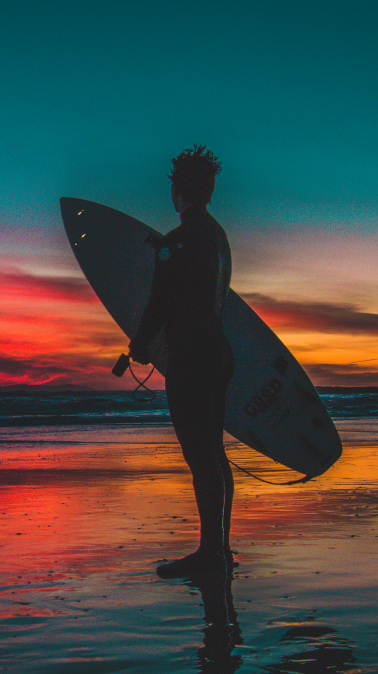 Silhouette de Femme Tenant Une Planche de Surf Sur la Plage Pendant le Coucher du Soleil. Wallpaper in 750x1334 Resolution