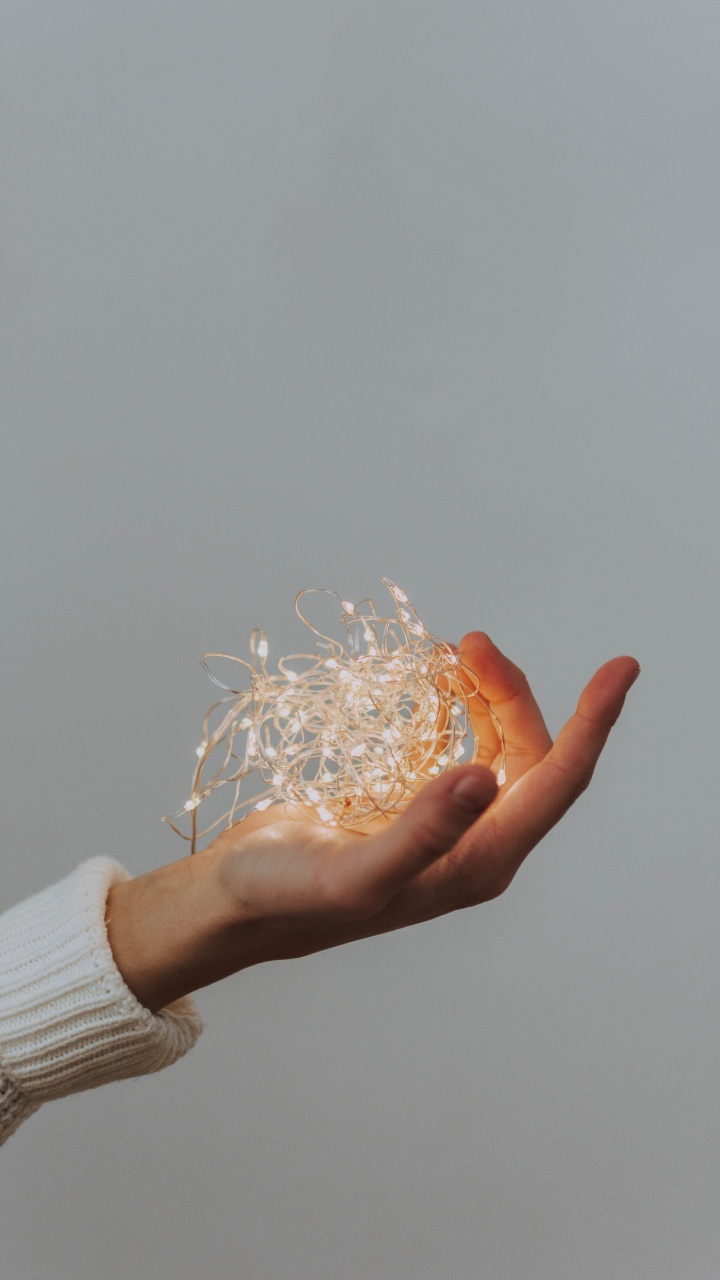 Person Holding White String Lights. Wallpaper in 720x1280 Resolution