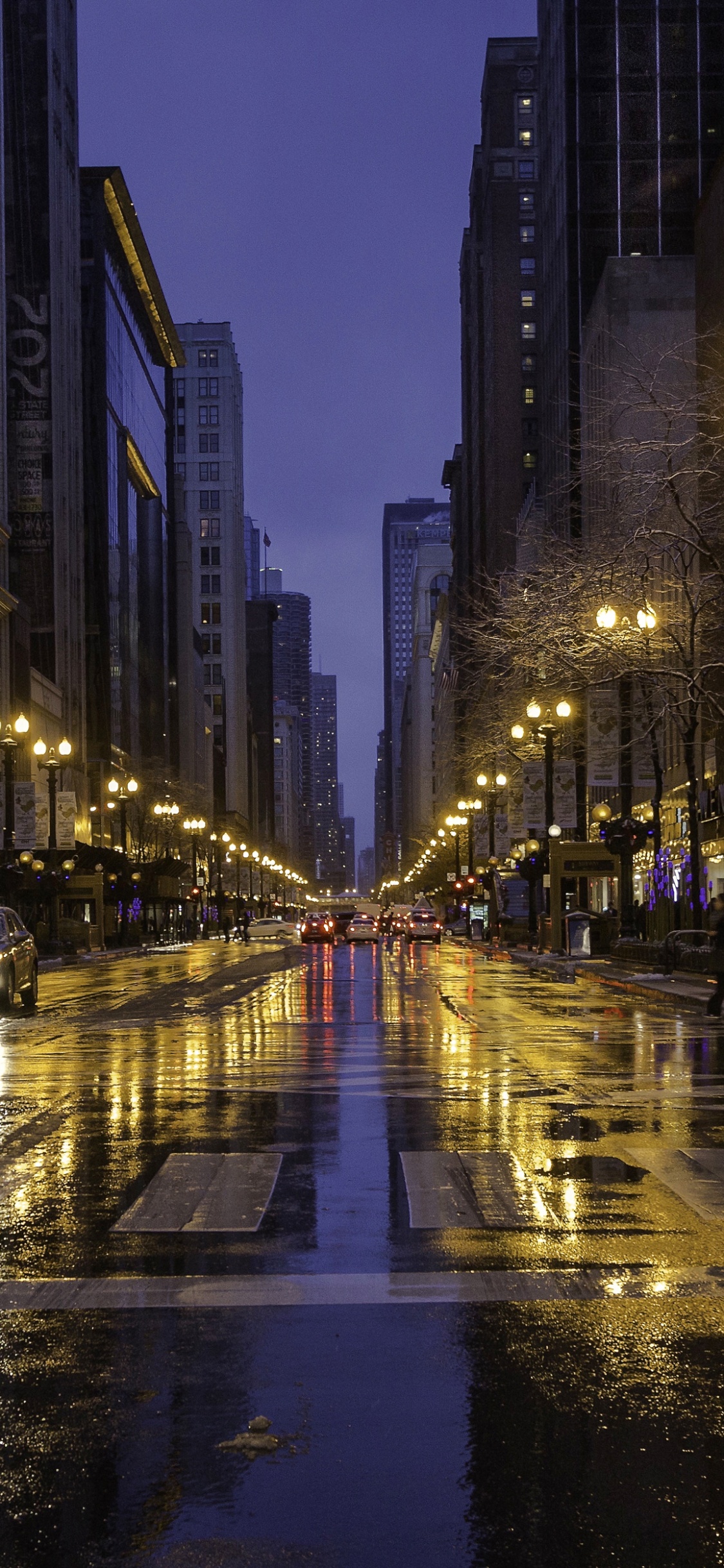 Voitures Sur Route Entre Les Immeubles de Grande Hauteur Pendant la Nuit. Wallpaper in 1125x2436 Resolution