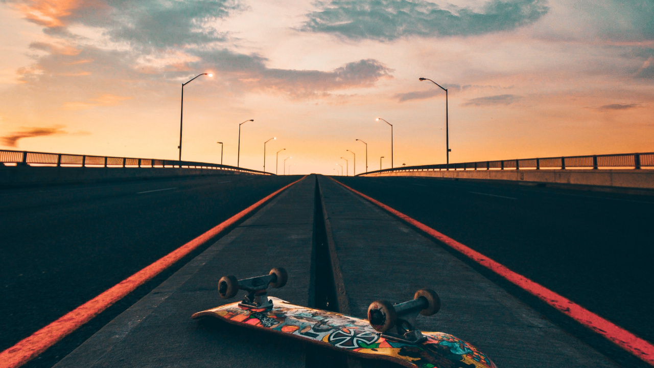 Man in Black Shirt Lying on Skateboard on Black Asphalt Road Under Gray Cloudy Sky During. Wallpaper in 1280x720 Resolution