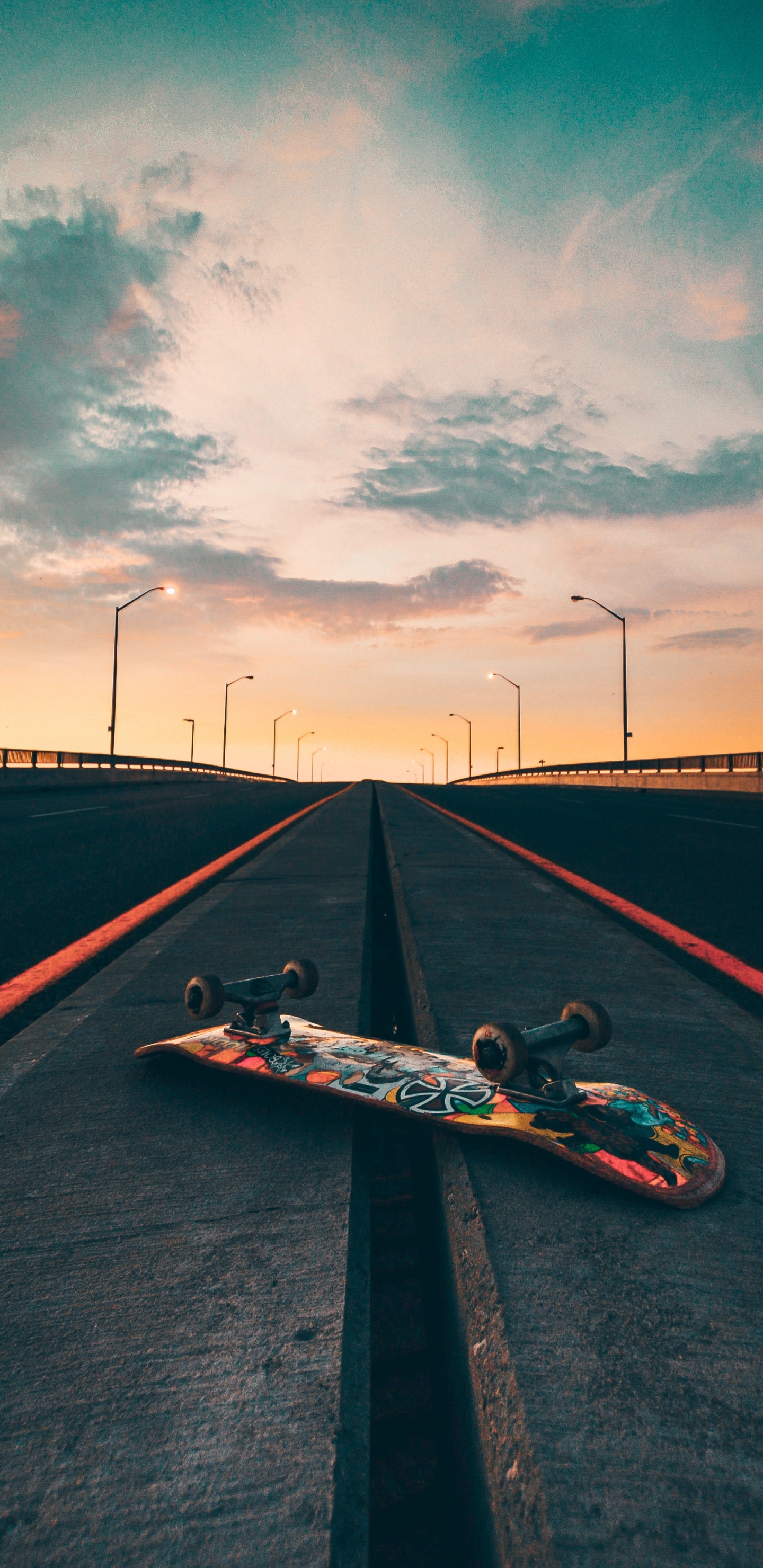 Man in Black Shirt Lying on Skateboard on Black Asphalt Road Under Gray Cloudy Sky During. Wallpaper in 1440x2960 Resolution