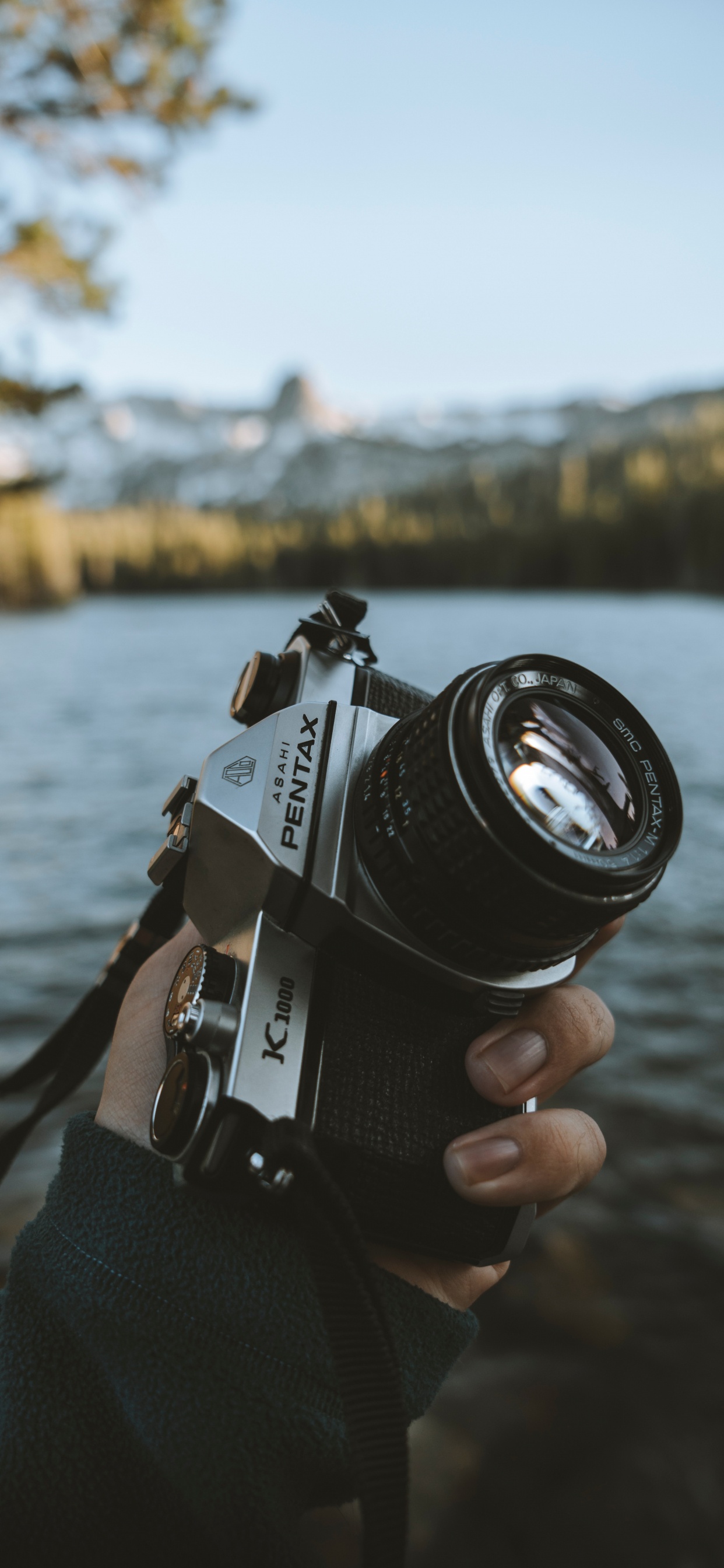 Person Mit Schwarzer Und Silberner DSLR-Kamera. Wallpaper in 1242x2688 Resolution