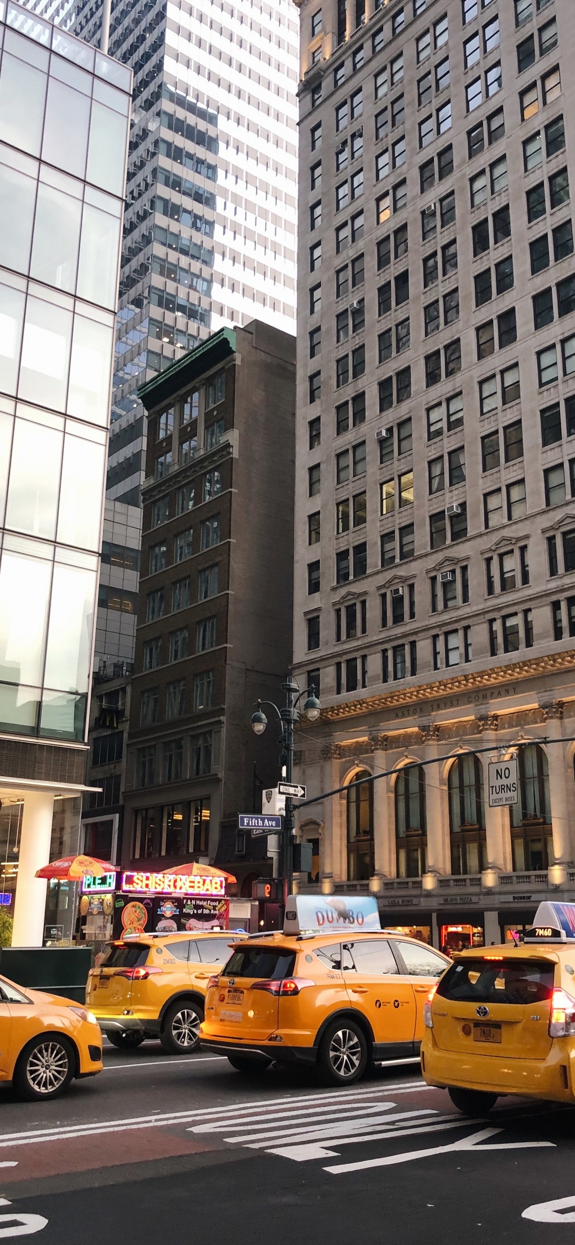 Taxi Amarillo en la Carretera Cerca de un Edificio Alto Durante el Día. Wallpaper in 1125x2436 Resolution