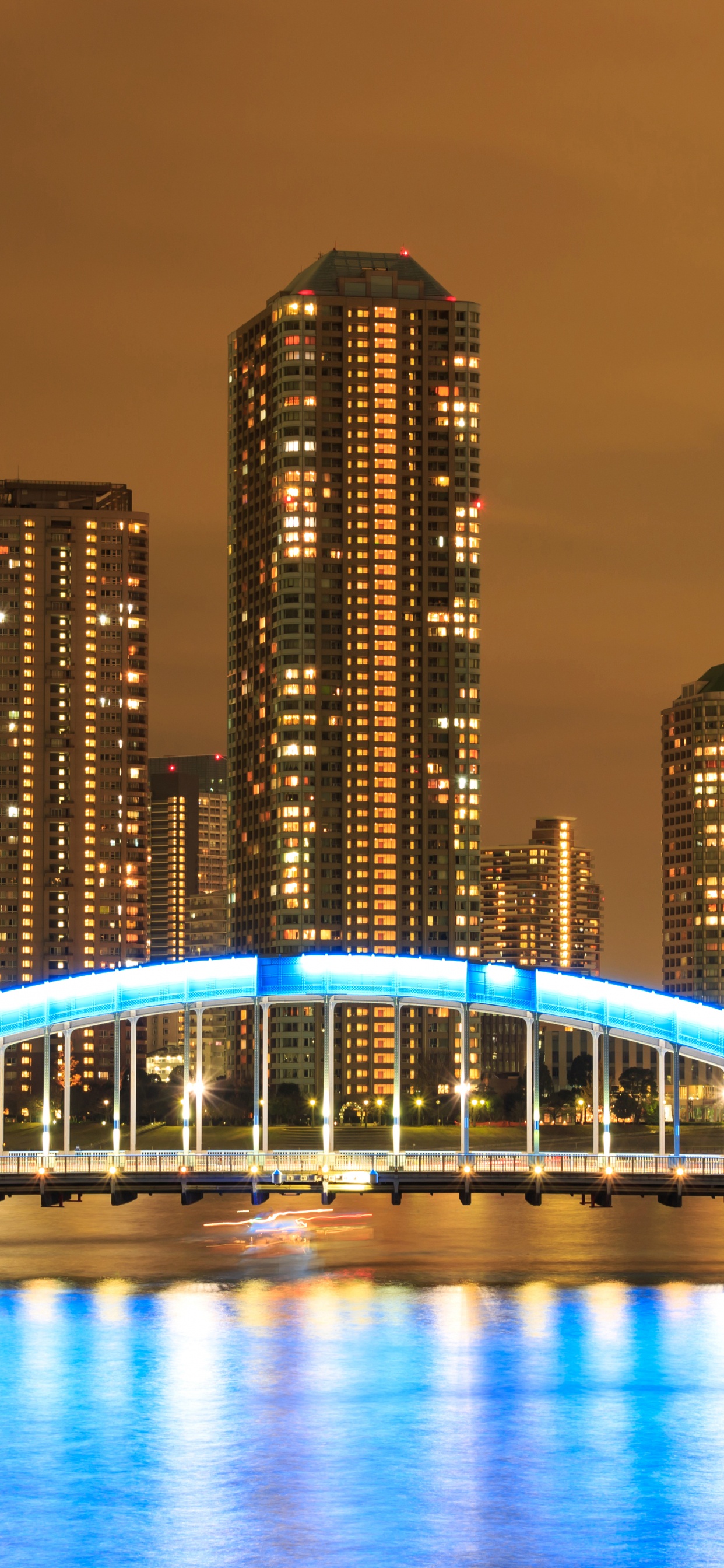 Lighted Bridge Over Body of Water Near City Buildings During Night Time. Wallpaper in 1242x2688 Resolution
