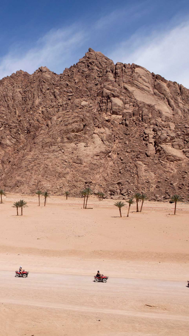 Personnes Marchant Sur la Plage Près de la Montagne Rocheuse Brune Pendant la Journée. Wallpaper in 750x1334 Resolution