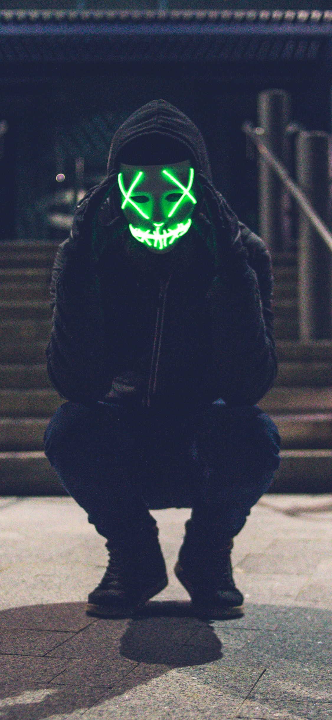Person in Black Hoodie Wearing Green Mask. Wallpaper in 1125x2436 Resolution