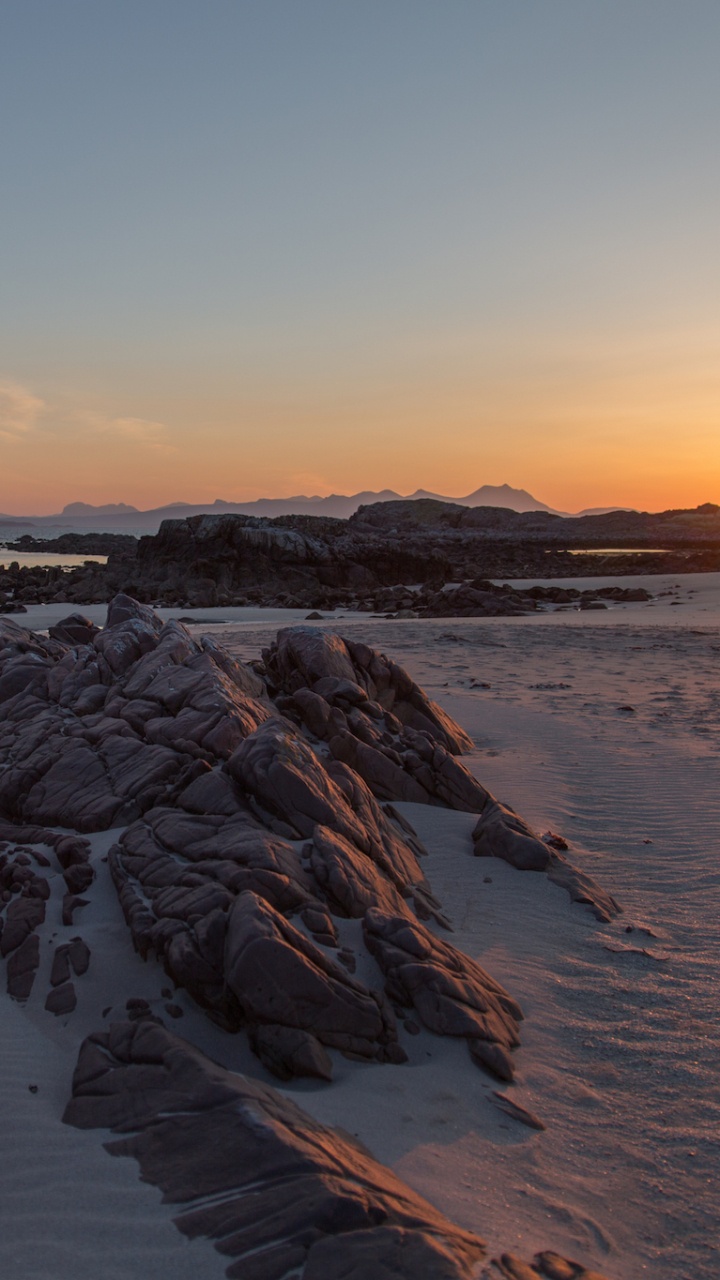 Rocky Shore During Sunset Under Orange Sky. Wallpaper in 720x1280 Resolution