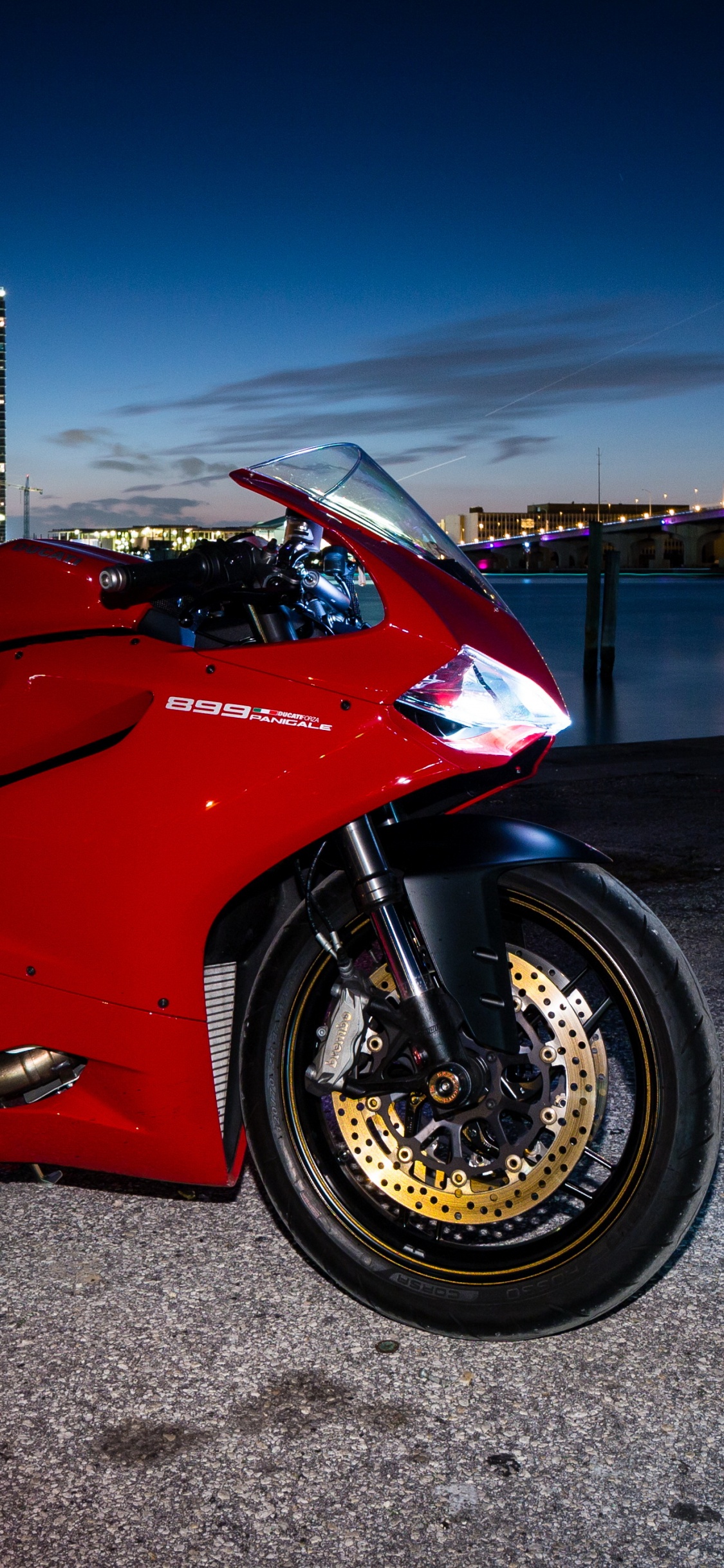 Rotes Und Schwarzes Sportfahrrad, Das Nachts Auf Grauem Betonpflaster Geparkt Ist. Wallpaper in 1125x2436 Resolution