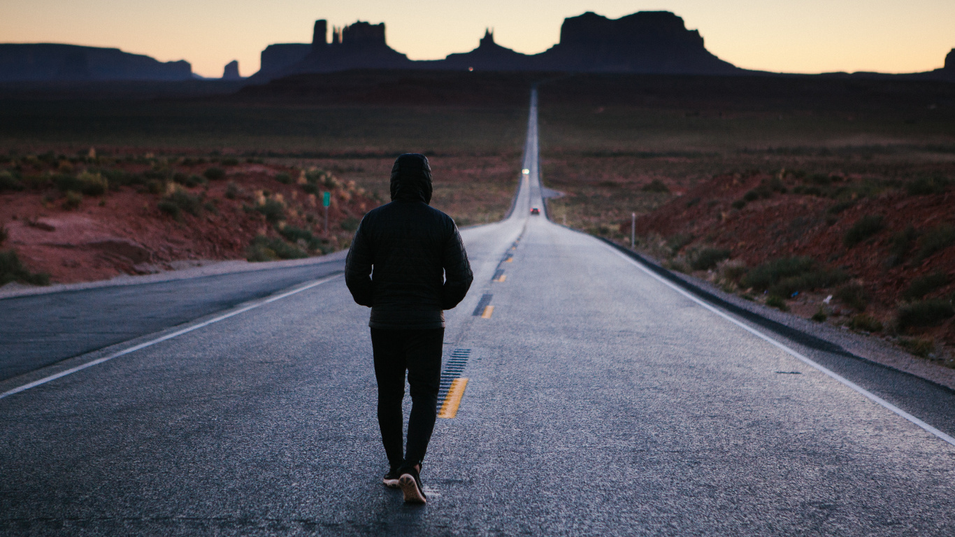 Hombre de Chaqueta Negra Caminando Por la Carretera Durante el Día. Wallpaper in 1366x768 Resolution