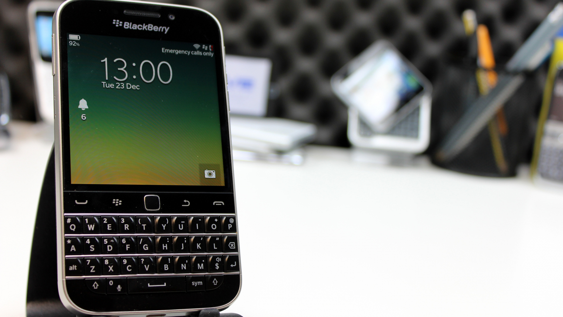 Download 1920x1080 Wallpaper Black Blackberry Qwerty Phone on White Table Black Blackberry Qwerty Phone on White Table. Wallpaper in 1920x1080 Resolution