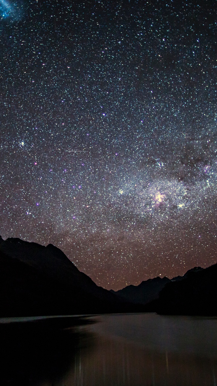 Body of Water Near Mountain Under Starry Night. Wallpaper in 720x1280 Resolution