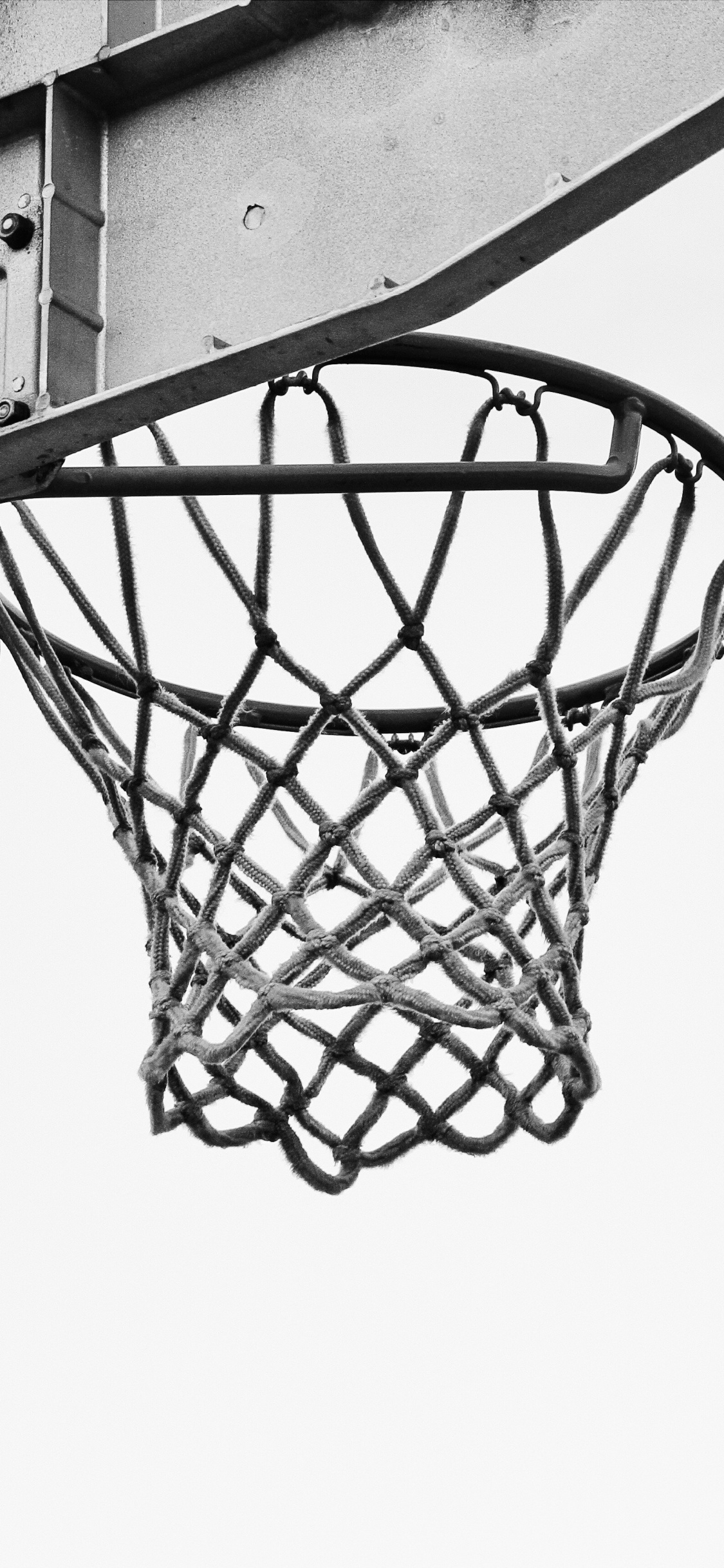 Basketball Auf Basketballkorb in Graustufenfotografie. Wallpaper in 1125x2436 Resolution