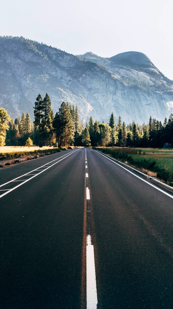 Gray Concrete Road Between Green Trees and Mountain During Daytime. Wallpaper in 720x1280 Resolution