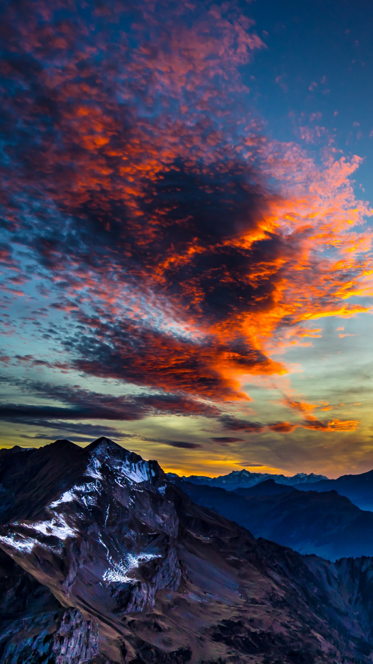 Schneebedeckter Berg Unter Orangefarbenem Und Blauem Himmel. Wallpaper in 750x1334 Resolution