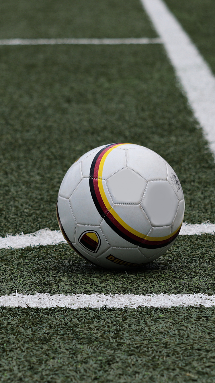 Weißer Und Gelber Fußball Auf Grünem Feld. Wallpaper in 750x1334 Resolution