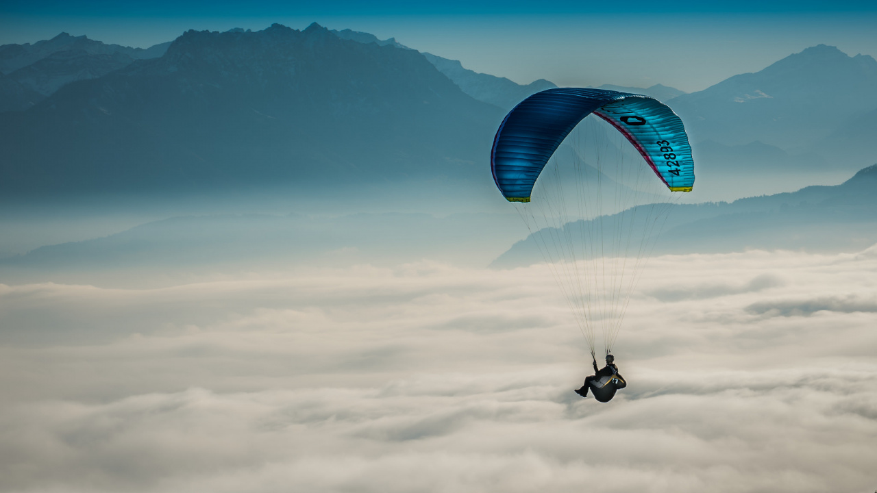 Person Riding Parachute Over Mountain Range. Wallpaper in 1280x720 Resolution