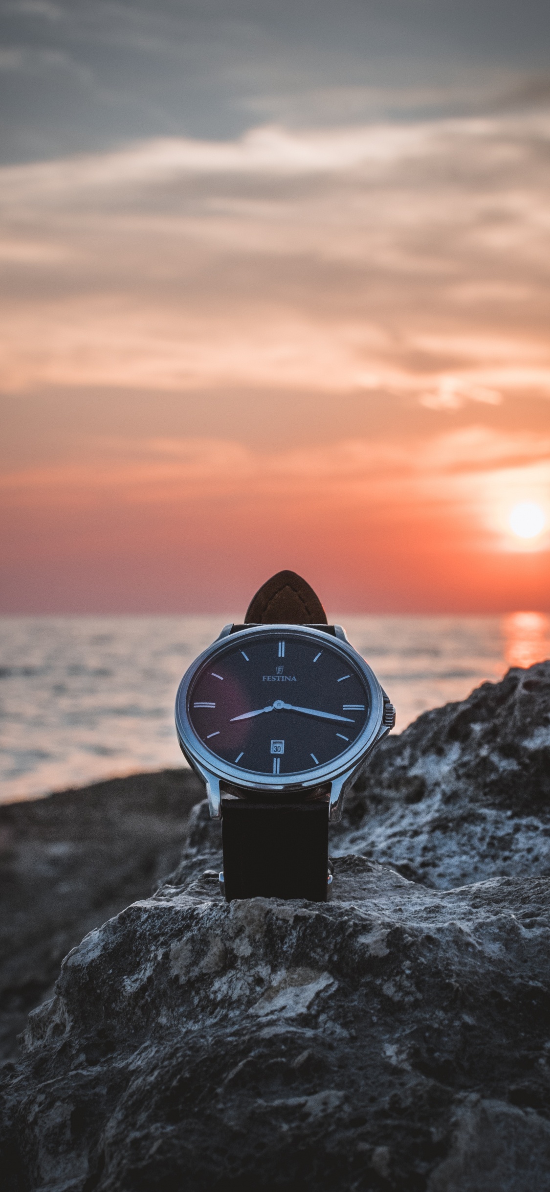 Black and White Analog Watch on Gray Rock Near Sea During Sunset. Wallpaper in 1125x2436 Resolution