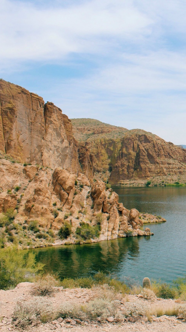 Montaña Rocosa Marrón Junto al Mar Azul Bajo un Cielo Azul Durante el Día. Wallpaper in 720x1280 Resolution