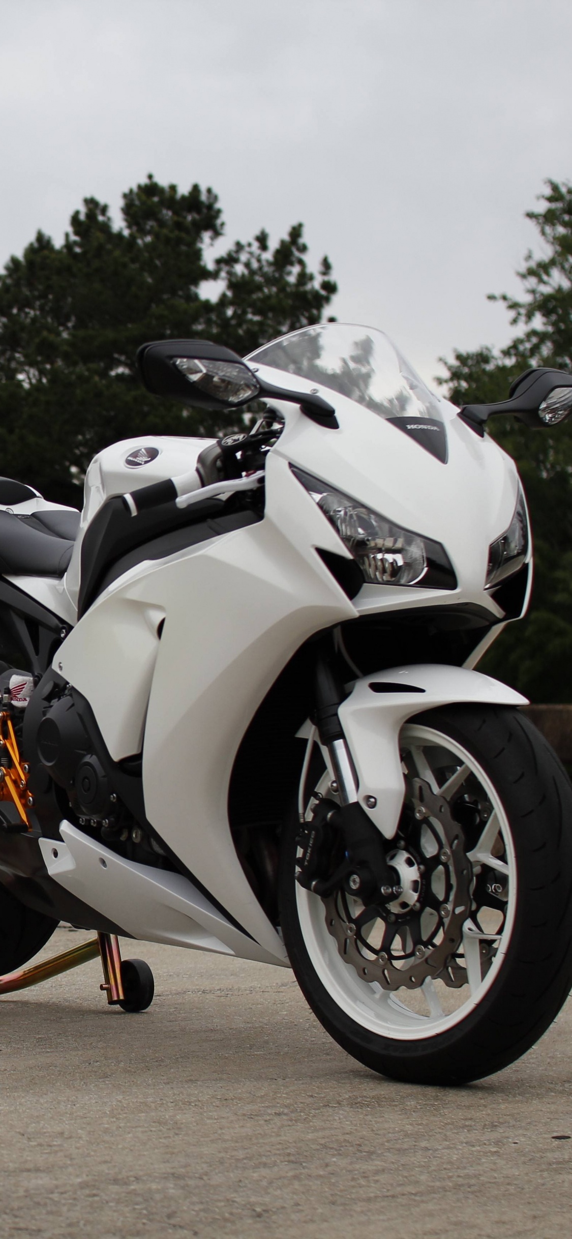 Black and White Sports Bike Parked on Brown Dirt Road During Daytime. Wallpaper in 1125x2436 Resolution