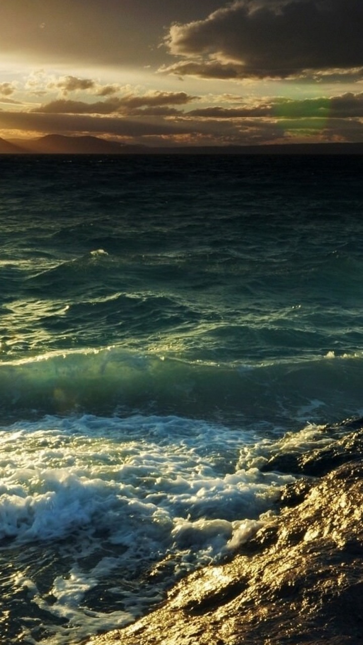 Ocean Waves Crashing on Shore During Sunset. Wallpaper in 720x1280 Resolution