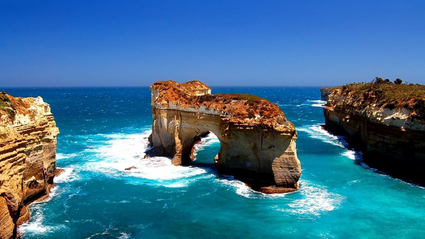 Brown Rock Formation on Blue Sea Under Blue Sky During Daytime. Wallpaper in 1366x768 Resolution